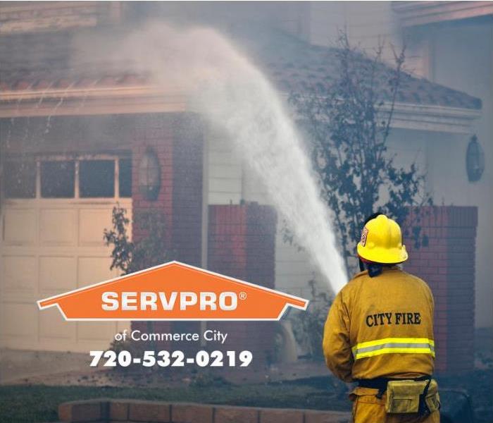 A firefighter is shown spraying water on a home to extinguish a fire.