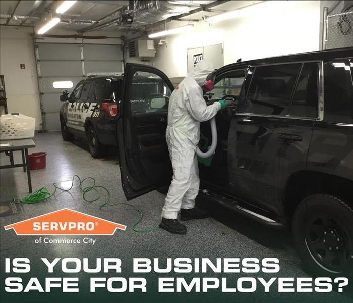 SERVPRO technician in PPE cleaning a cop car