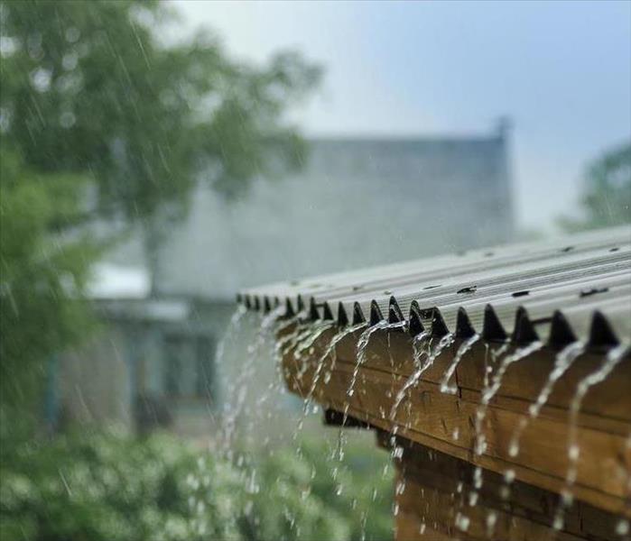 Rain pouring off the roof of a house